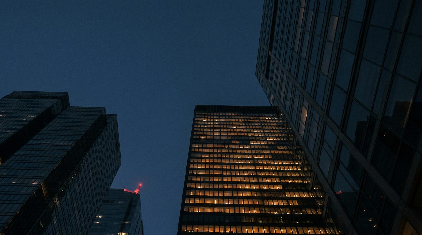 Office towers in a financial district at dusk with lit windows forming a grid